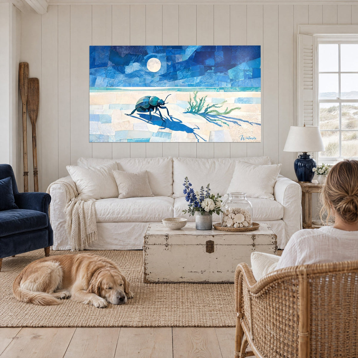 Tableau scarabée bleu marchant sur du sable clair sous une pleine lune, au-dessus d'un canapé dans un salon lumineux