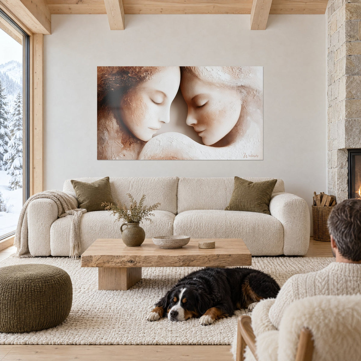 Gemälde zwei Gesichter eng umschlungen, Stirn an Stirn, strukturiertes Beige und Weiß, schwarzer Hund liegend, über einem Sofa in einem hellen Wohnzimmer