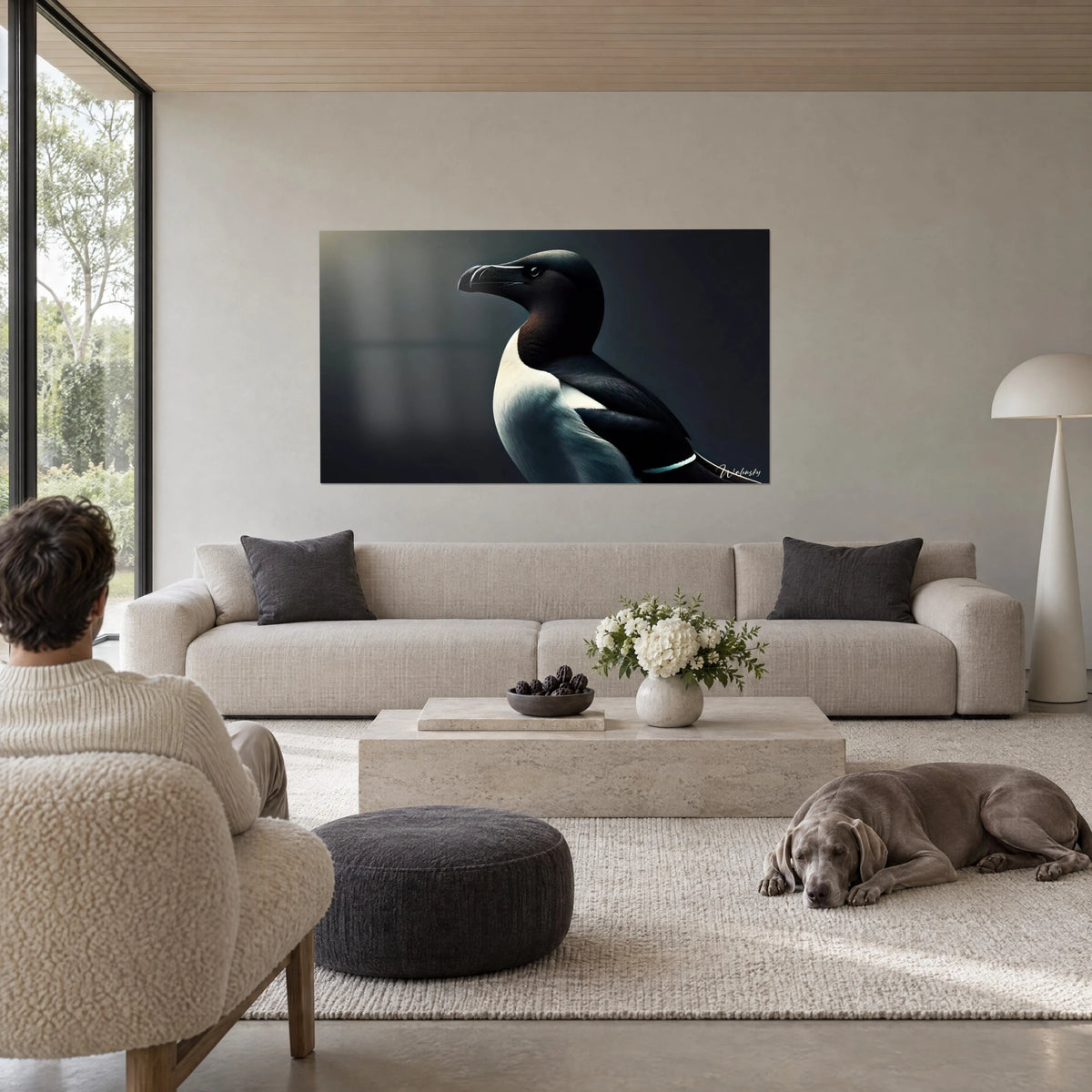 Cuadro pingüino con plumaje blanco y negro, de perfil sobre fondo gris pizarra, con un Weimaraner tumbado, encima de un sofá en un salón luminoso
