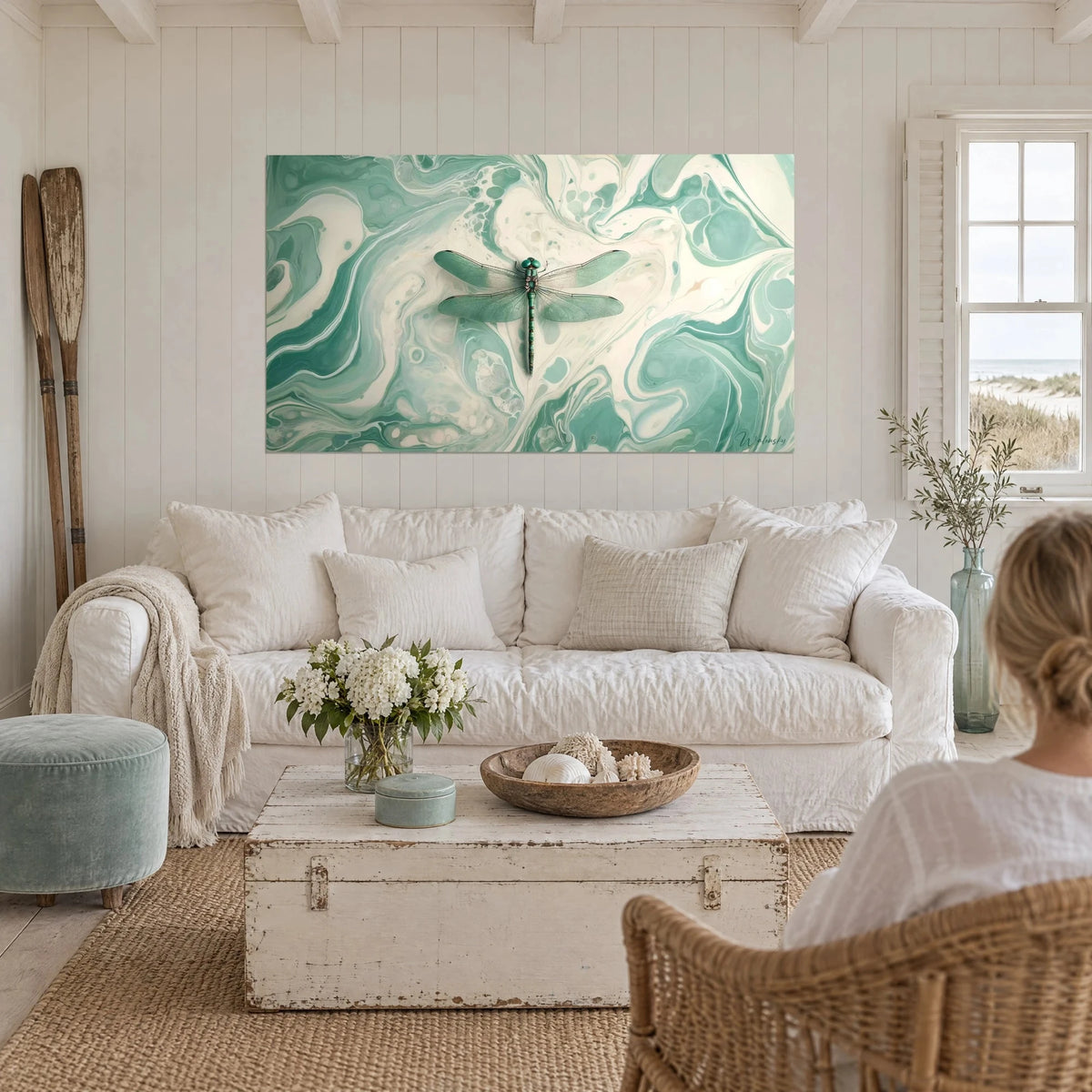 Tableau libellule émeraude posée sur marbrures turquoise et crème, au-dessus d'un canapé dans un salon lumineux