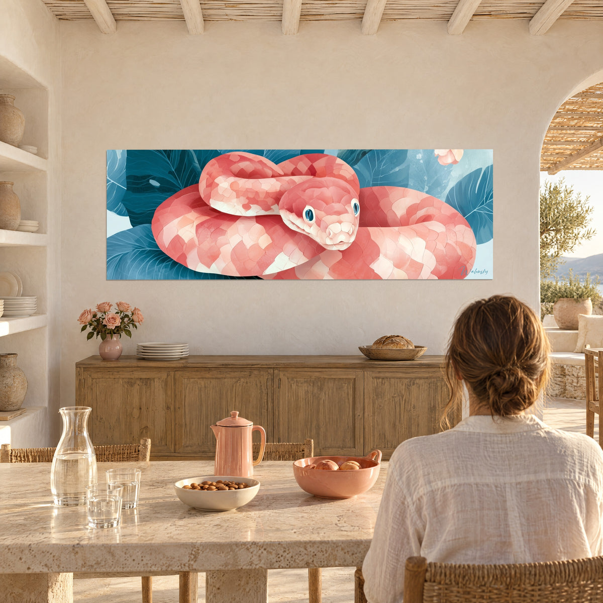 Wall art coiled boa with salmon and ivory sheen, deep blue-green foliage, facing a woman seen from behind seated in a Mediterranean home