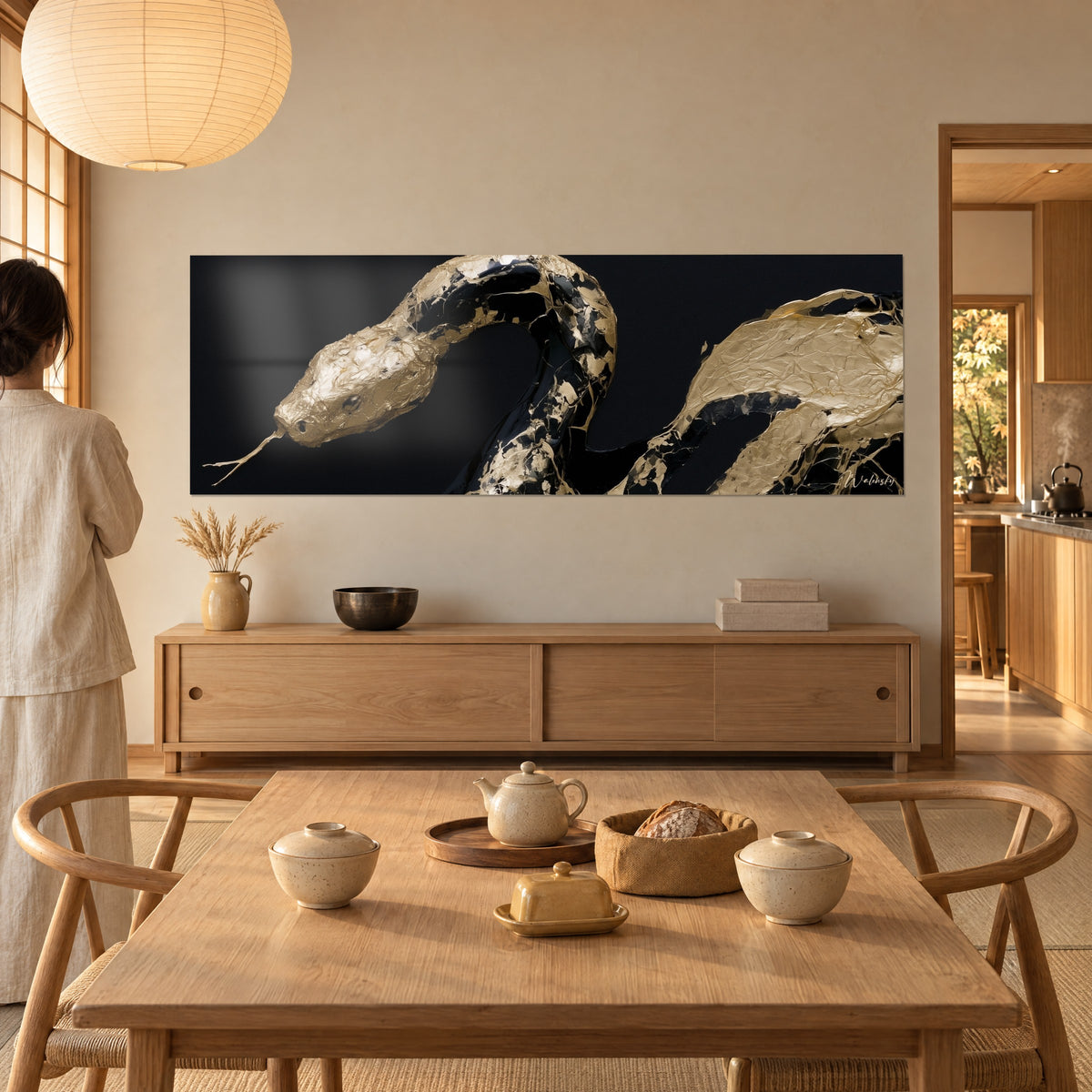 Schilderij van een gouden metalen adder met donkere reflecties, kop naar links gestrekt, crèmekleurige muur, dressoir van licht hout en een theepot