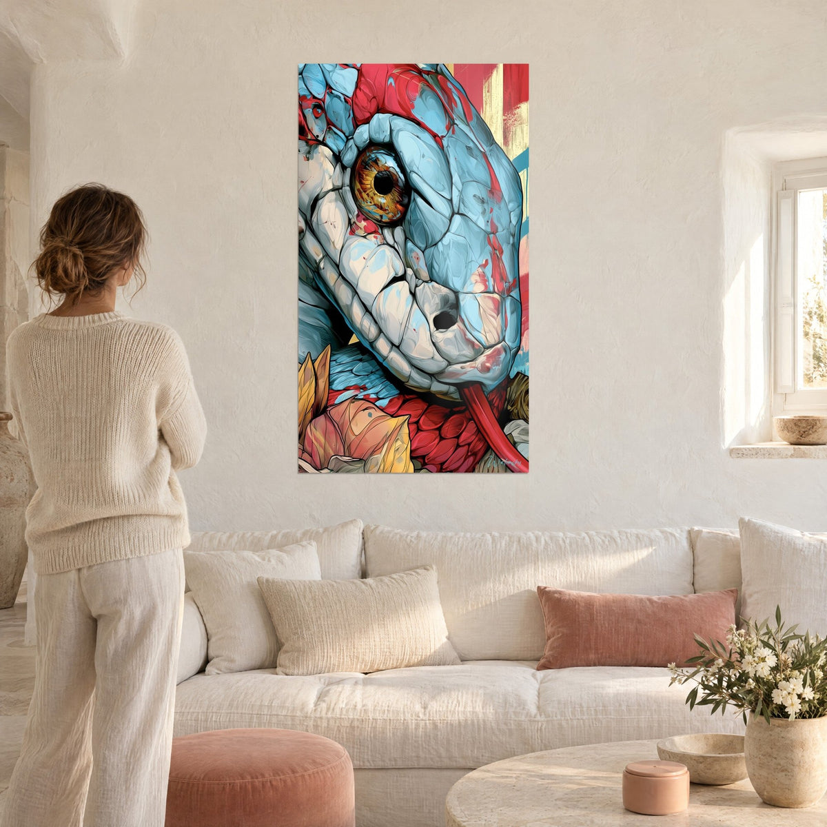 Wall art sky-blue snake with an amber eye, red and cream scales, a woman seen from behind above a sofa in a bright living room