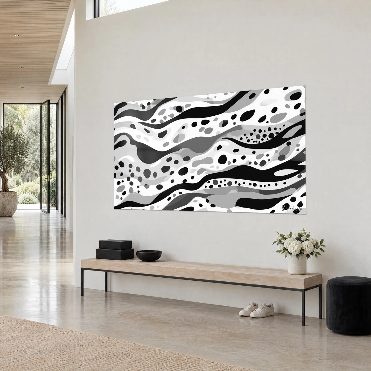 Cuadro de serpentinas onduladas en negro y blanco salpicadas de lunares grises, vista de tres cuartos de un banco de madera, pared beige