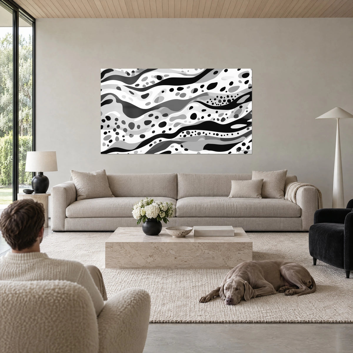 Cuadro de motivo moteado en blanco y negro con olas grises, hombre de espaldas, Weimaraner tumbado, encima de un sofá en un salón luminoso