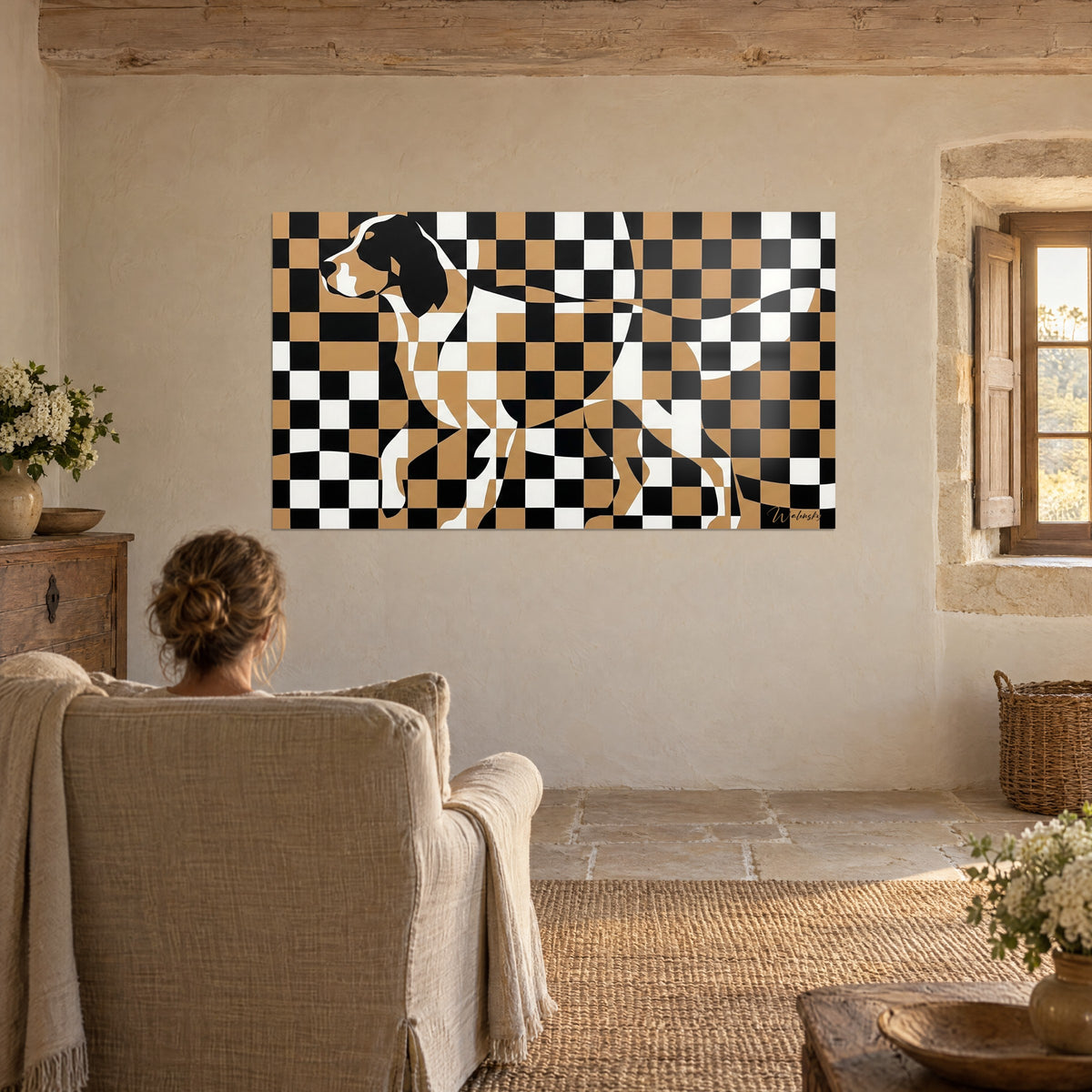 Wall art canine portrait in ochre, black and white squares, a woman seen from behind in an armchair, lime-washed walls and stone window