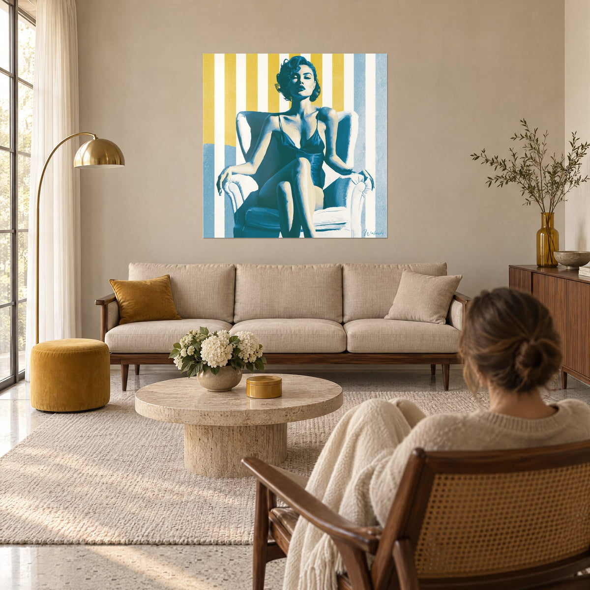 Quadro pin-up in quadrato blu anatra, seduta su una poltrona bianca davanti a uno sfondo a righe giallo senape, una donna di spalle, sopra un divano in un soggiorno luminoso