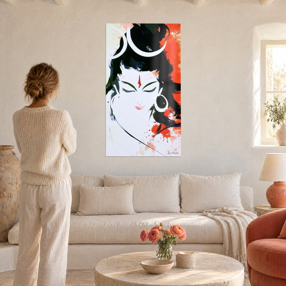 Quadro volto di Shiva con gli occhi chiusi, mezzelune bianche e fronte rosso vivo, donna di spalle, sopra un divano in un soggiorno luminoso