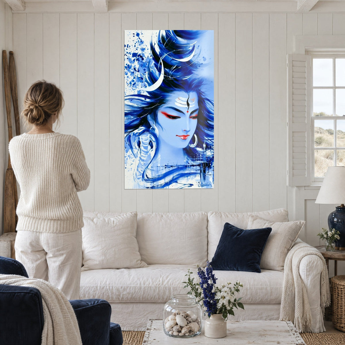 Tableau Shiva au visage bleu glacier, croissant de lune blanc dans la chevelure indigo, lèvres rouges, au-dessus d'un canapé dans un salon lumineux