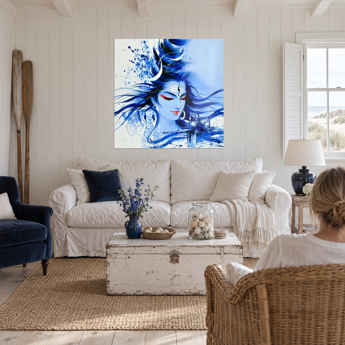 Wall art Shiva face in cobalt blue with red eyes, ink splashes, above a sofa in a bright living room