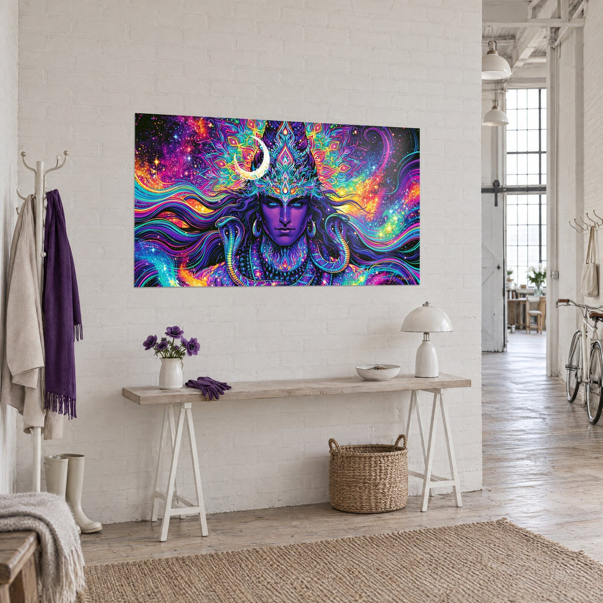 Wall art of a Hindu deity with a crown of orange and turquoise mandalas, pink nebula in the background, on a white wall beside a console table