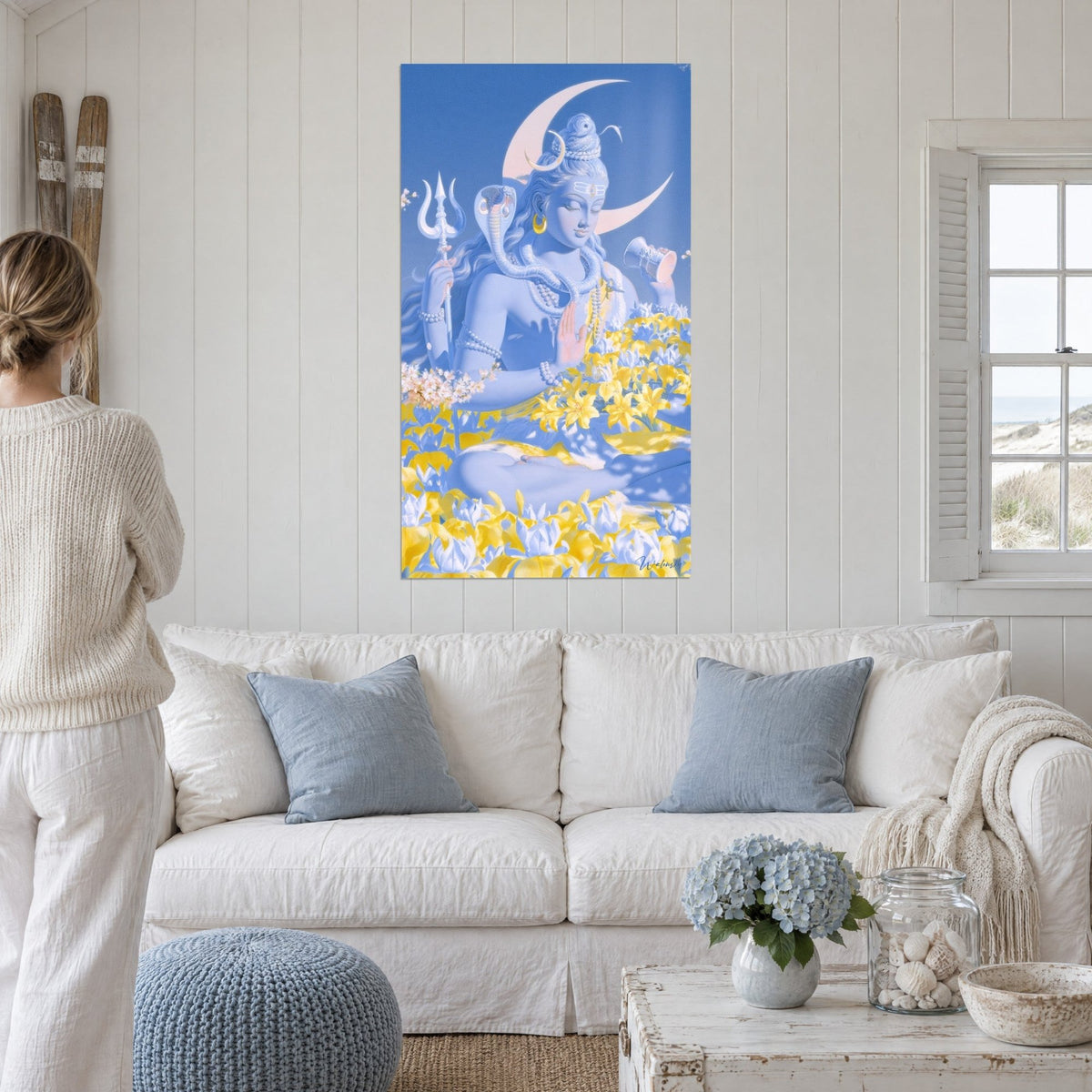 Wall art of Shiva meditating in periwinkle blue and lemon yellow, rosy crescent moon, above a sofa in a bright living room