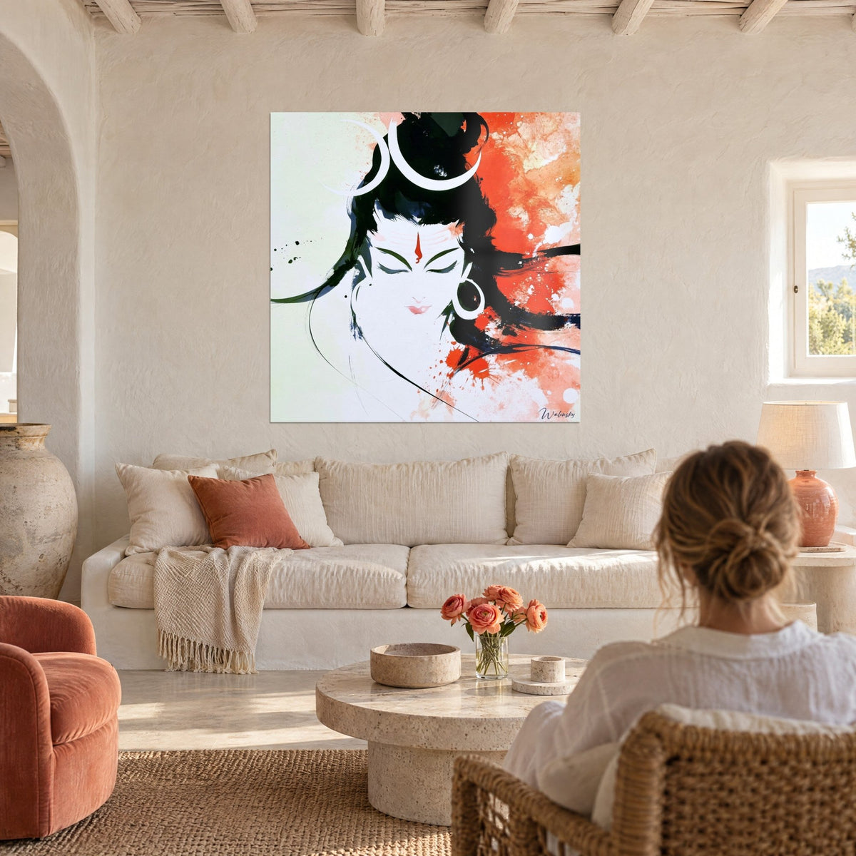 Tableau divinité aux yeux clos, croissant blanc et éclaboussures orange et noires, au-dessus d'un canapé dans un salon lumineux