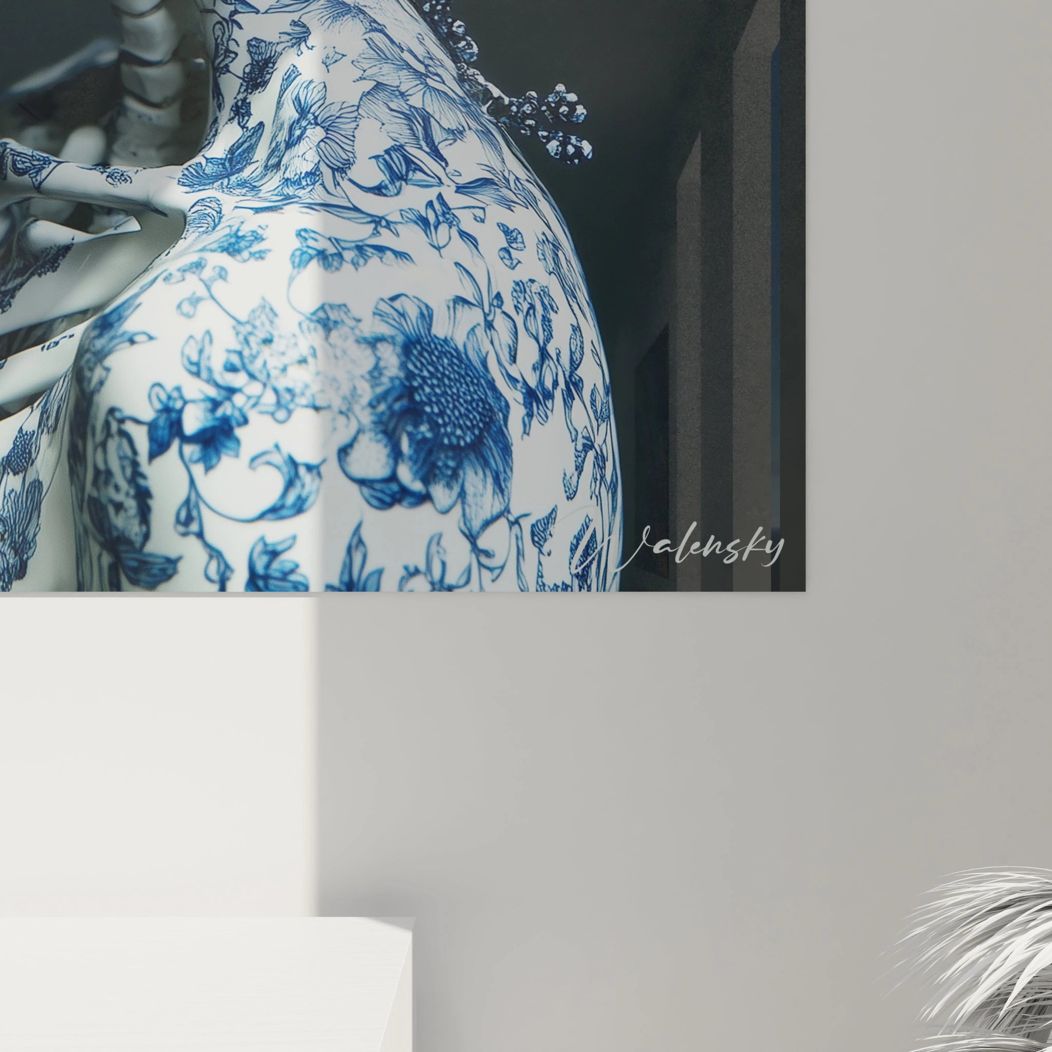 Tableau porcelaine crâne aux finitions bleu et blanc, alliant art funéraire et tradition céramique. L'œuvre présente un crâne anatomique décoré de motifs floraux délicats, avec une structure vertébrale visible et des éléments sculpturaux de papillons et fleurs en suspension.
