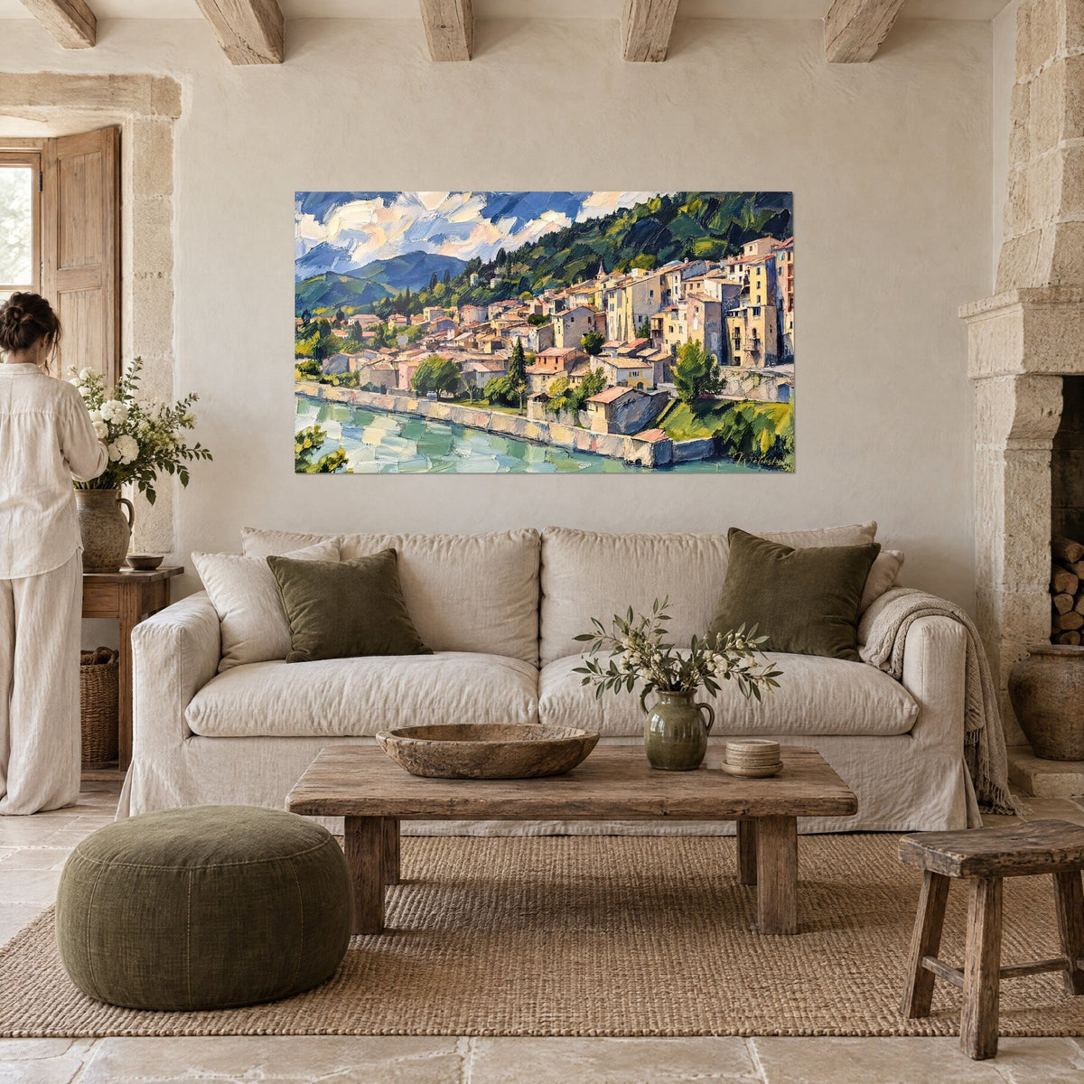 Gemälde Provenzalisches Dorf in Ocker und Blau am Wasser, gelbe Fassaden und rosa Dächer, über einem Sofa in einem hellen Wohnzimmer