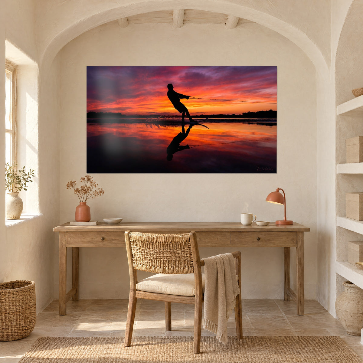 Quadro tramonto infuocato su un lago, sagoma scura con la corda tesa, riflesso ramato, scrivania in legno e arco a volta