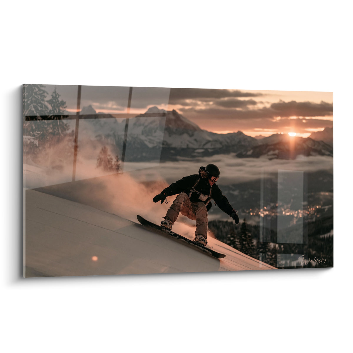 Snowboardeur en tenue noire dévalant une pente, ciel ocre et montagnes anthracite au coucher du soleil