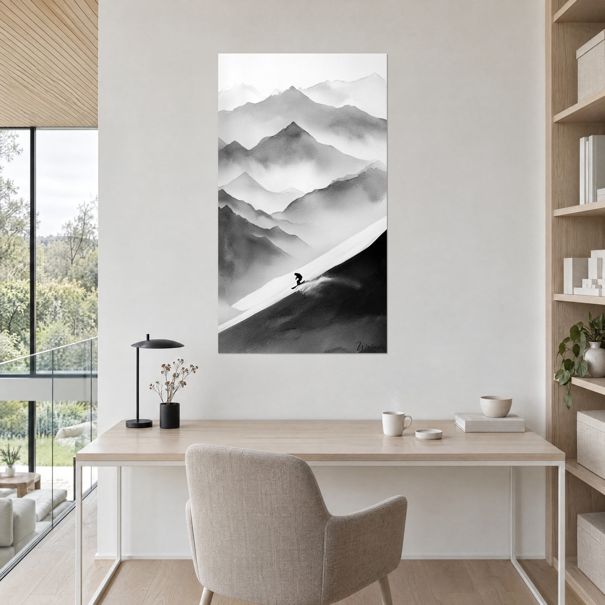 Wall art of a mountain range in grey and white gradients, shadow of a snowboarder, hung above a light wood desk