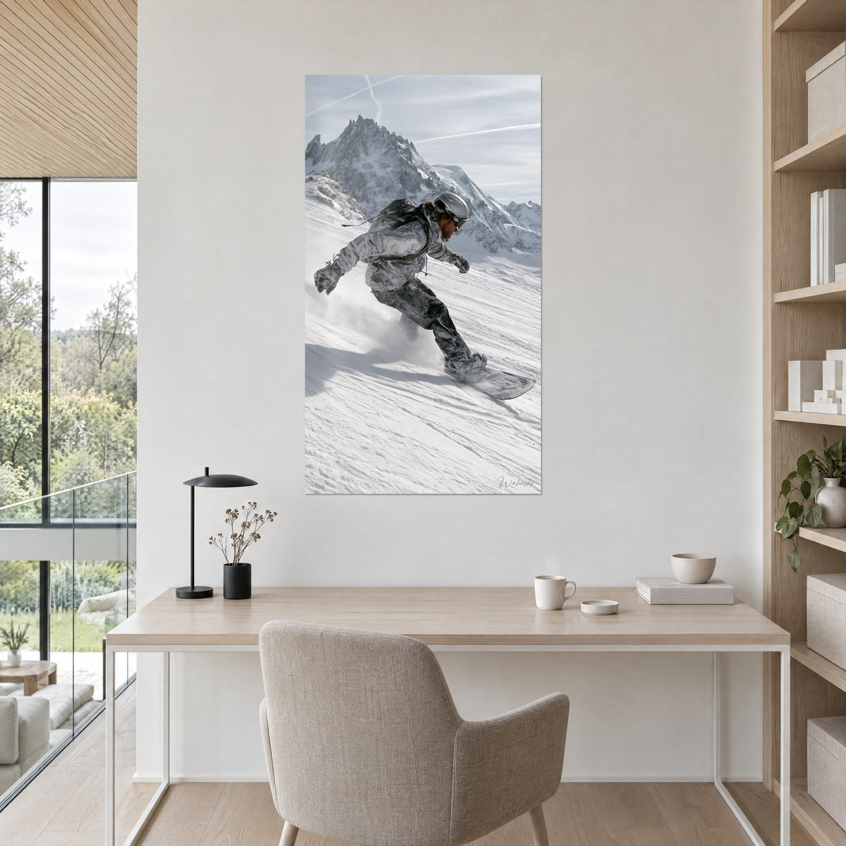 Wall art snowboarder mid-turn, metallic grey helmet and dazzling snow, rocky peak in the background, on the wall of a bright office next to a shelf