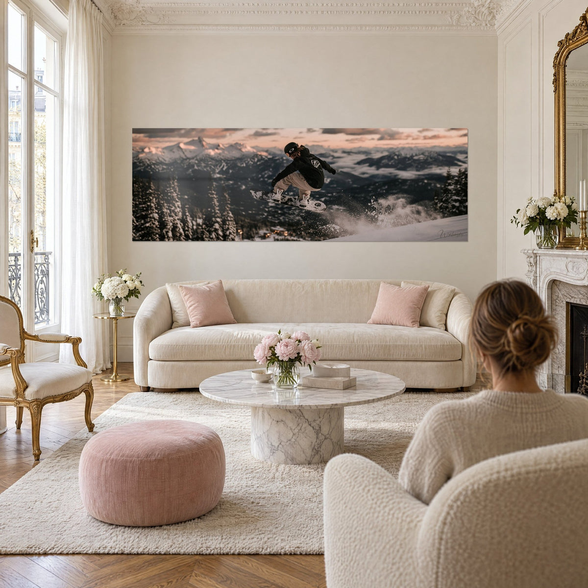 Gemälde Snowboarder in schwarzem Overall springend, rosa Himmel und blau schimmernde verschneite Gipfel, über einem Sofa in einem hellen Wohnzimmer