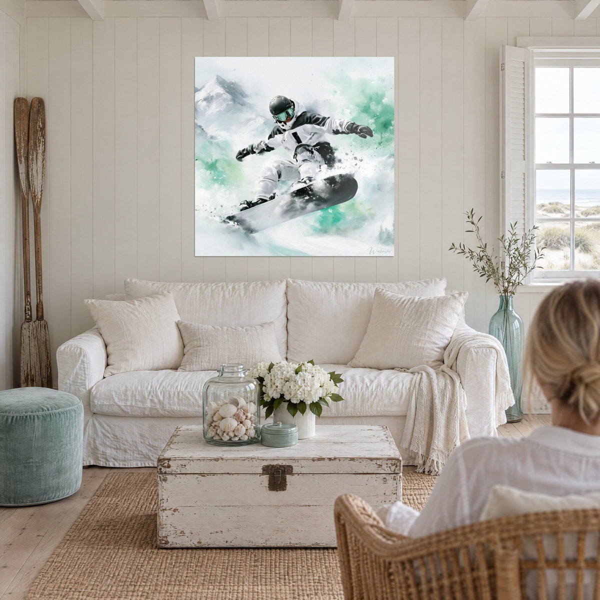 Wall art of a snowboarder in a white and black suit leaping, mint green clouds, above a sofa in a bright living room