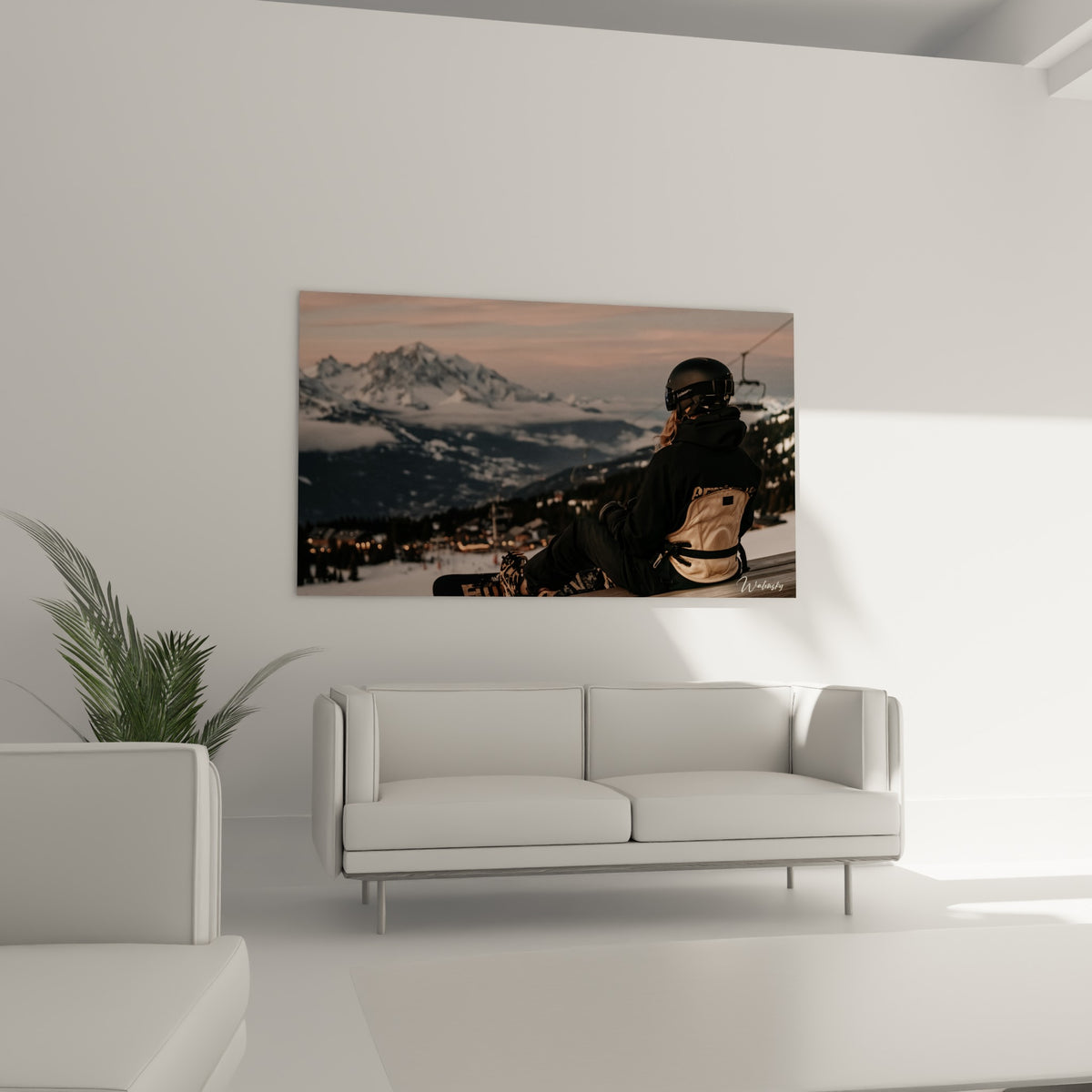 Rider assise sur son snowboard devant des pics anthracite, au-dessus d'un canapé dans un salon lumineux