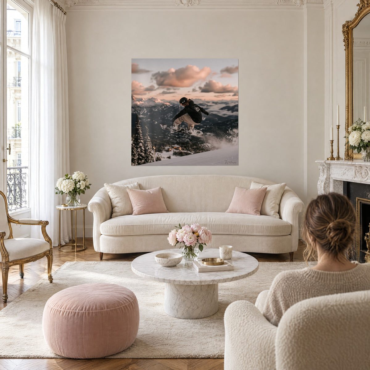 Schilderij van een snowboarder midden in de sprong, zwarte jas en beige broek, roze en crèmekleurige lucht, boven een bank in een lichte woonkamer