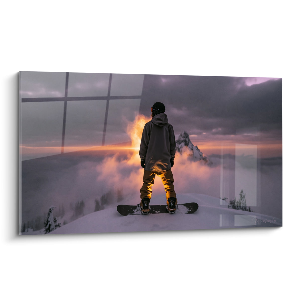 Snowboardeur de dos face à un sommet enneigé, ciel anthracite et lumière orangée intense