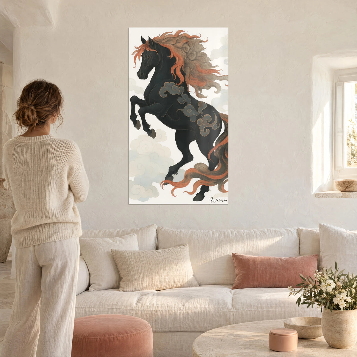 Cuadro de un caballo negro encabritado con crines cobrizas, nubes grises enroscadas, mujer de espaldas, encima de un sofá en un salón luminoso
