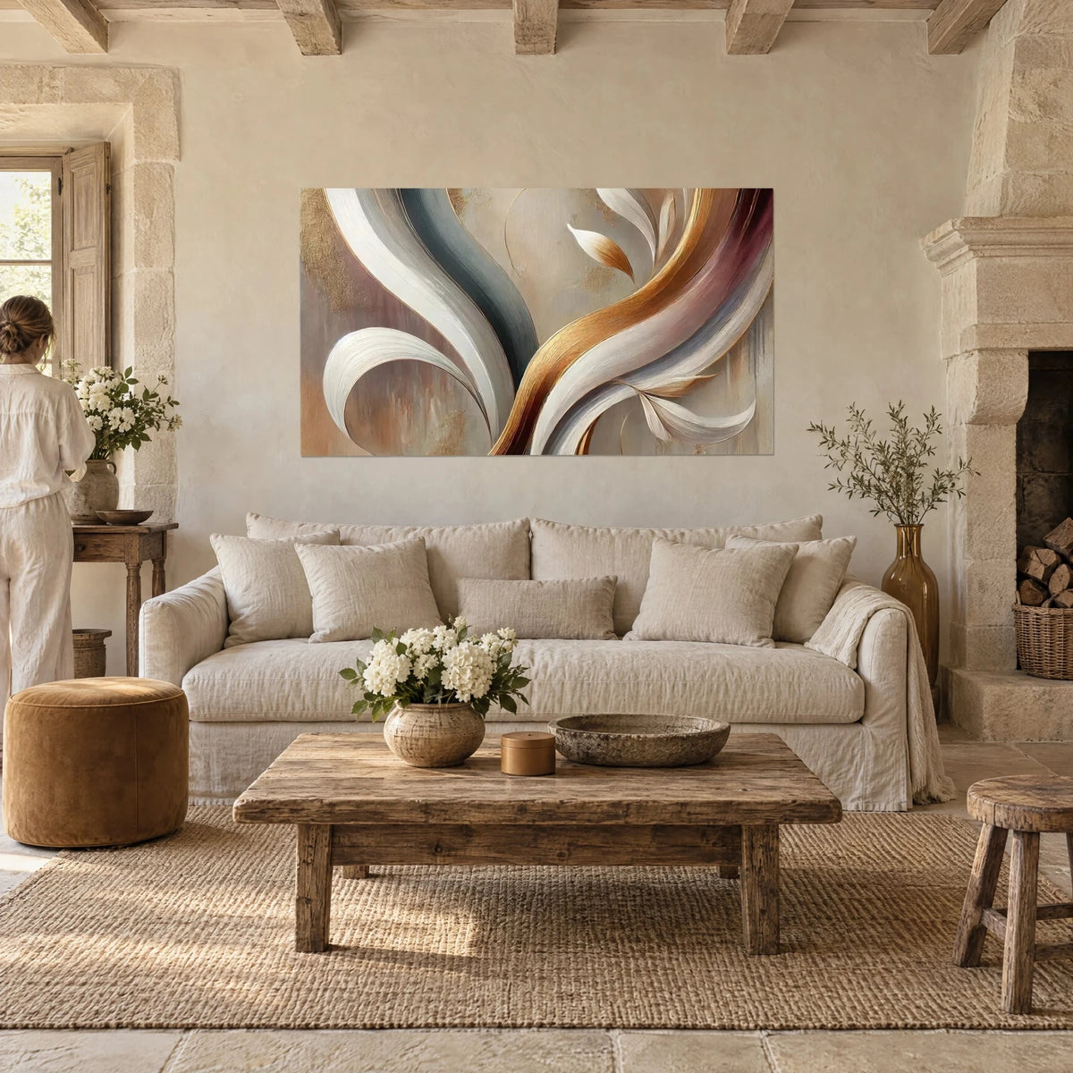 Wall art with ivory and copper ribbons undulating on a sand background, a woman seen from behind, above a sofa in a bright living room