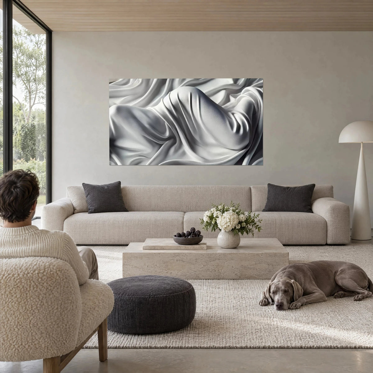 Tableau silhouette drapée sous un voile de soie gris perle et ivoire, plis profonds, au-dessus d'un canapé dans un salon lumineux