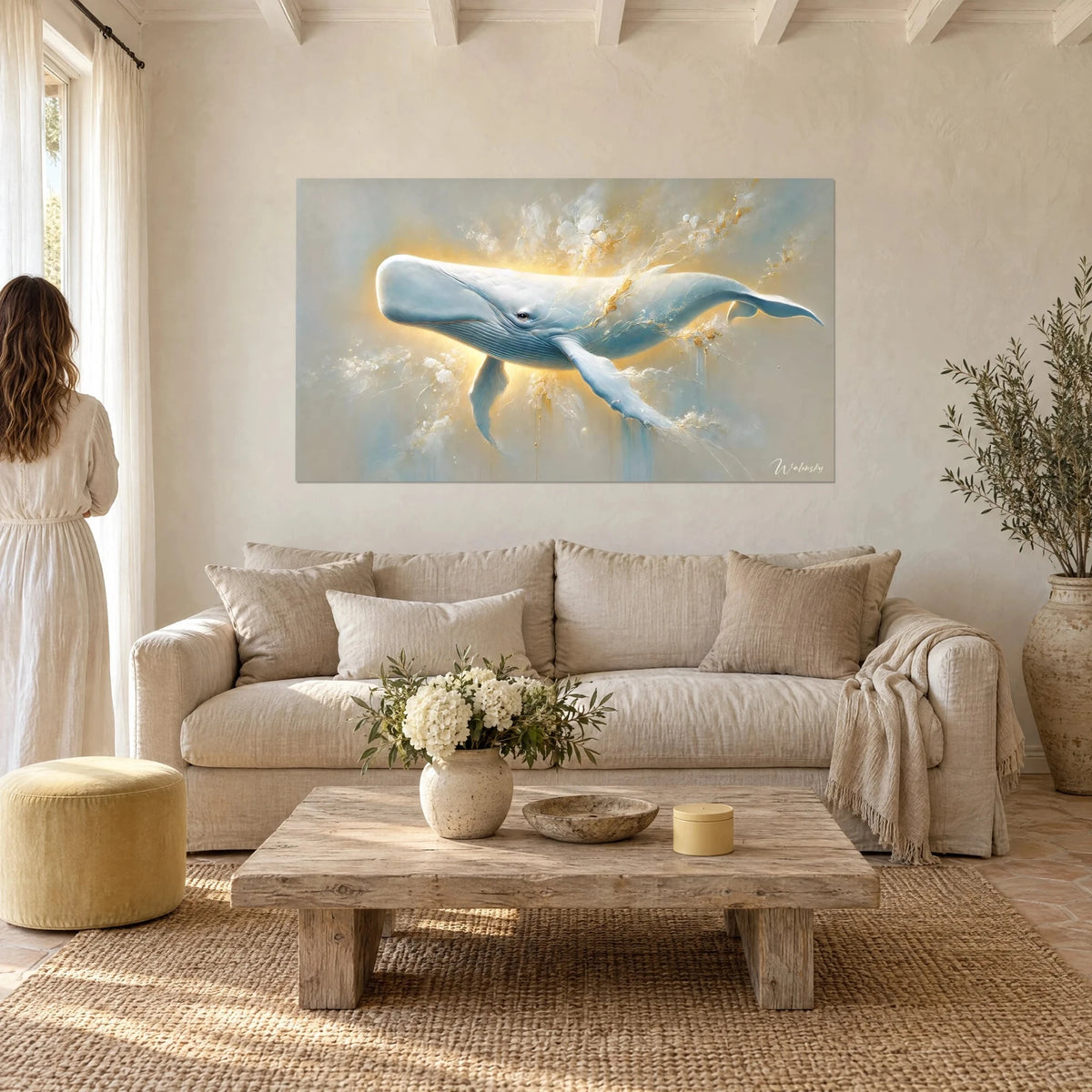 Cuadro cachalote blanco envuelto en un brillo dorado, aletas azul cielo y fondo beige, con dos personas de espaldas, sobre un sofá en un salón luminoso