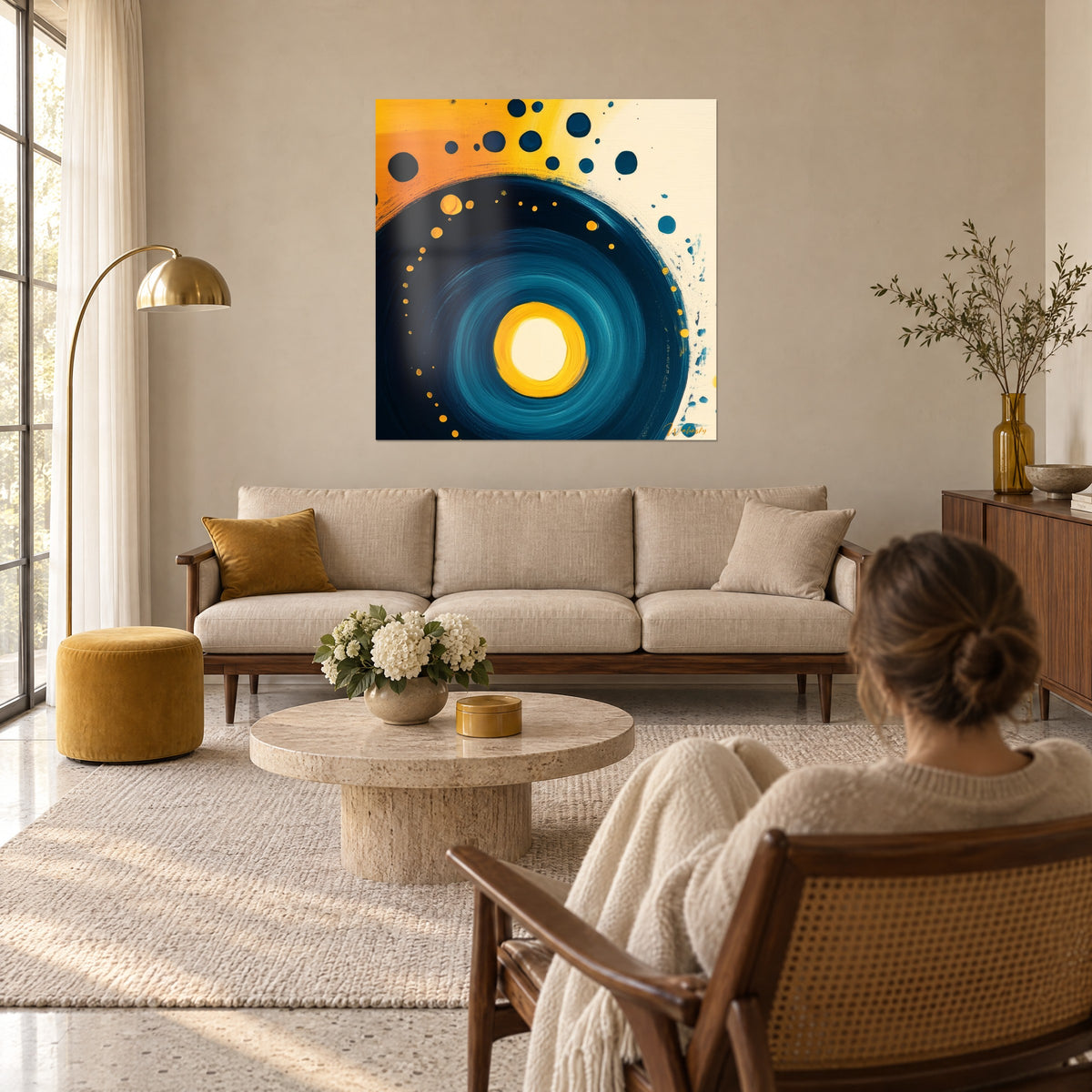 Cuadro espiral azul noche perfilada con lunares amarillo mostaza, centro crema, mujer de espaldas, encima de un sofá en un salón luminoso
