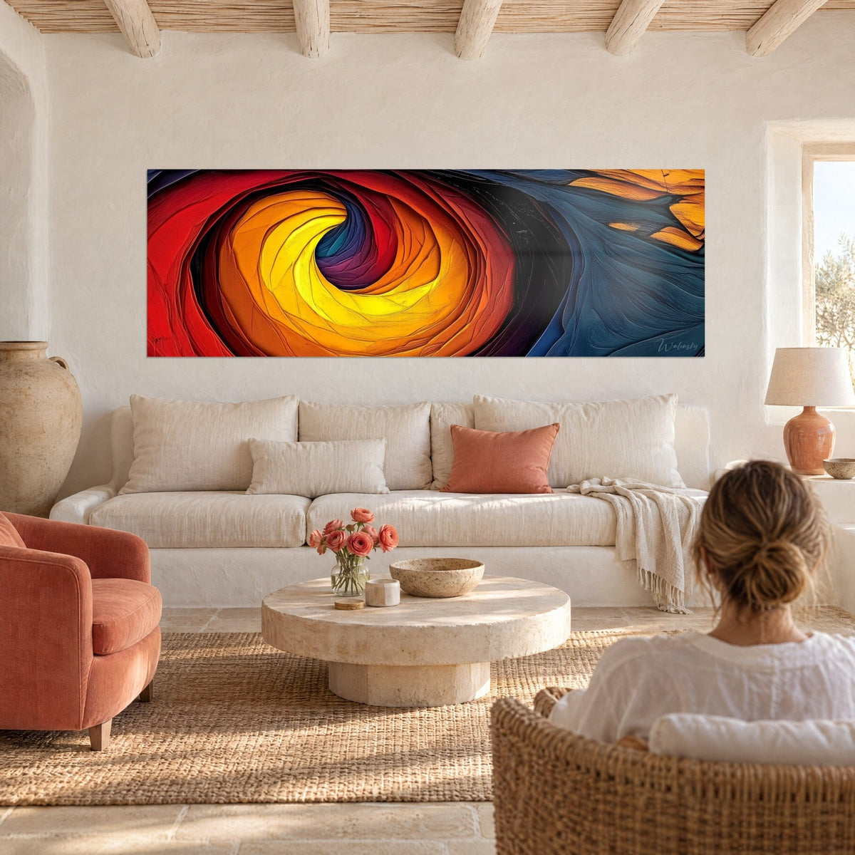 Tableau tourbillon de feu rouge et jaune ocre, bleu pétrole à droite, femme de dos, au-dessus d'un canapé dans un salon lumineux