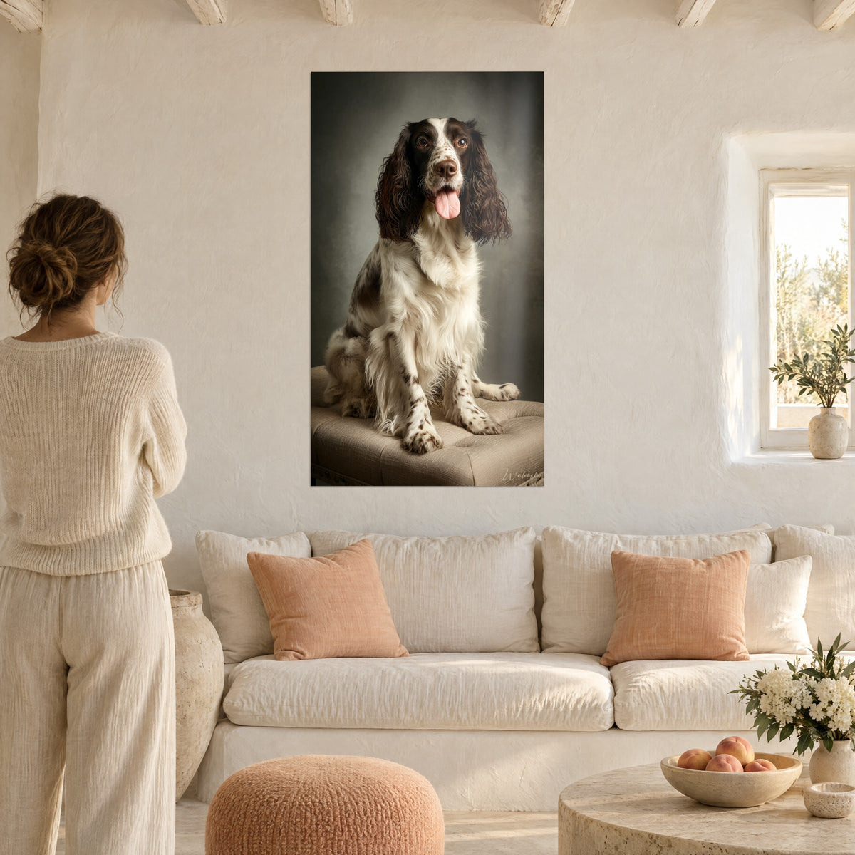 Wall art brown and white springer spaniel, tongue hanging out, seated on a beige pouf in front of a sofa in a bright living room