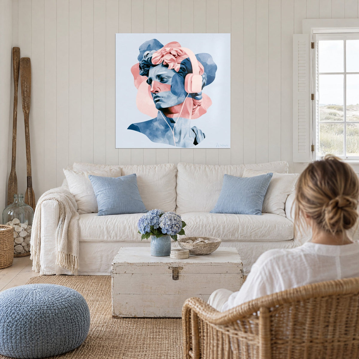Tableau statue antique au casque rose poudré, profil bleu ardoise et corail, au-dessus d'un canapé dans un salon lumineux