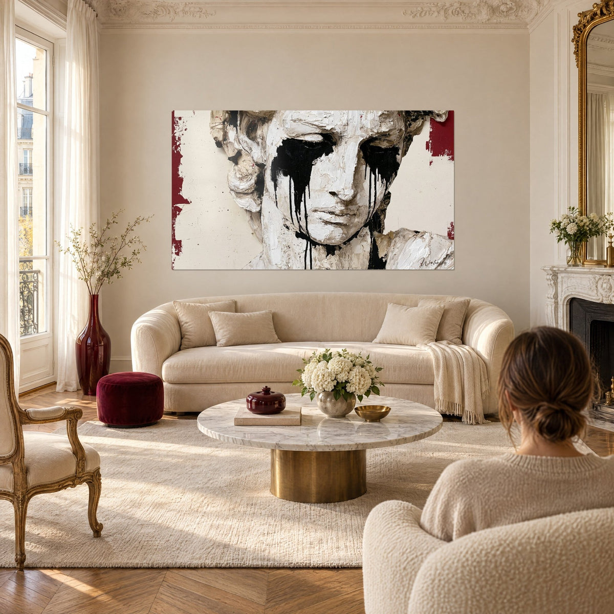 Tableau buste de plâtre blanc aux larmes d'encre noire, bords rouge bordeaux, au-dessus d'un canapé dans un salon lumineux