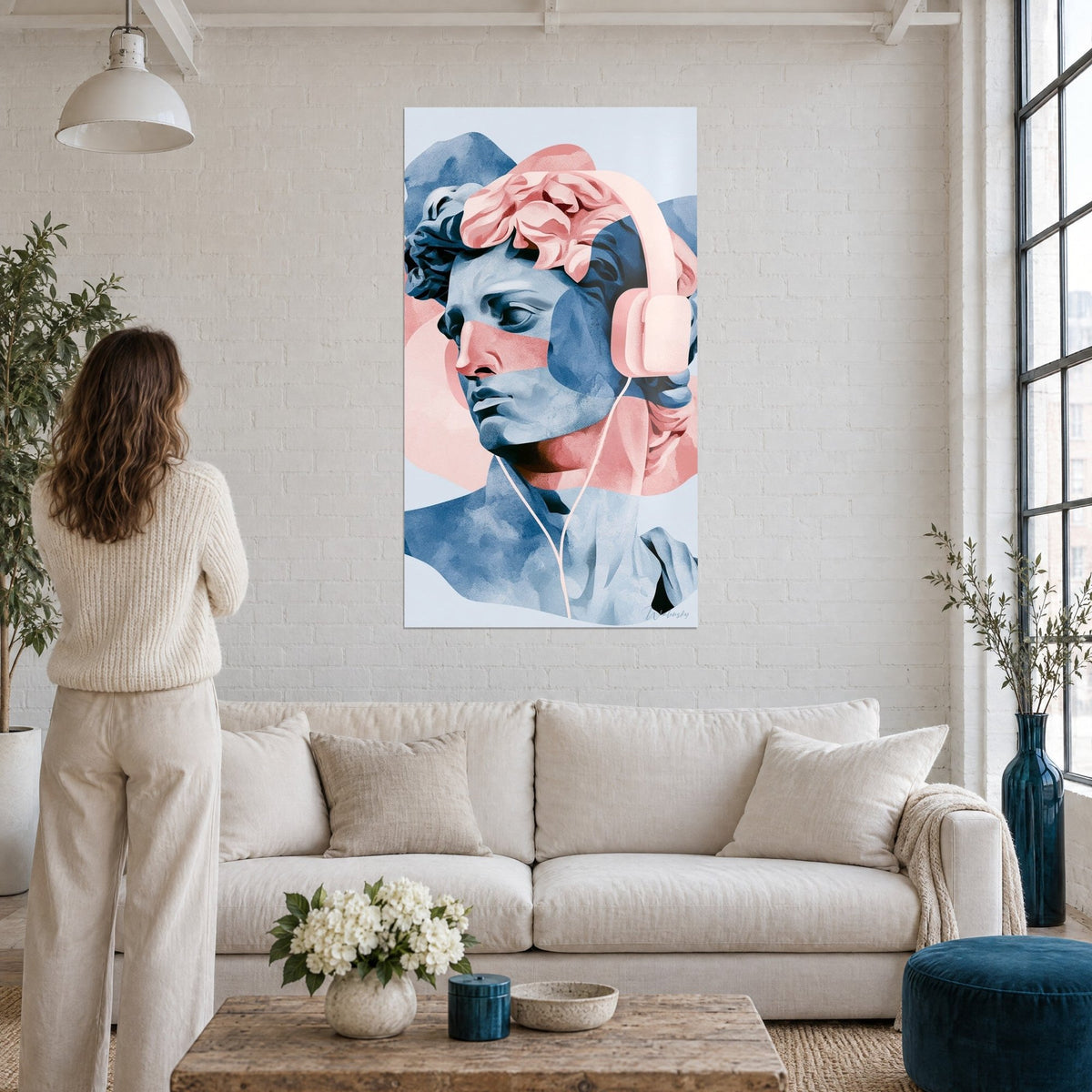Cuadro de busto antiguo en azul y rosa con auriculares, mujer de espaldas, encima de un sofá en un salón luminoso