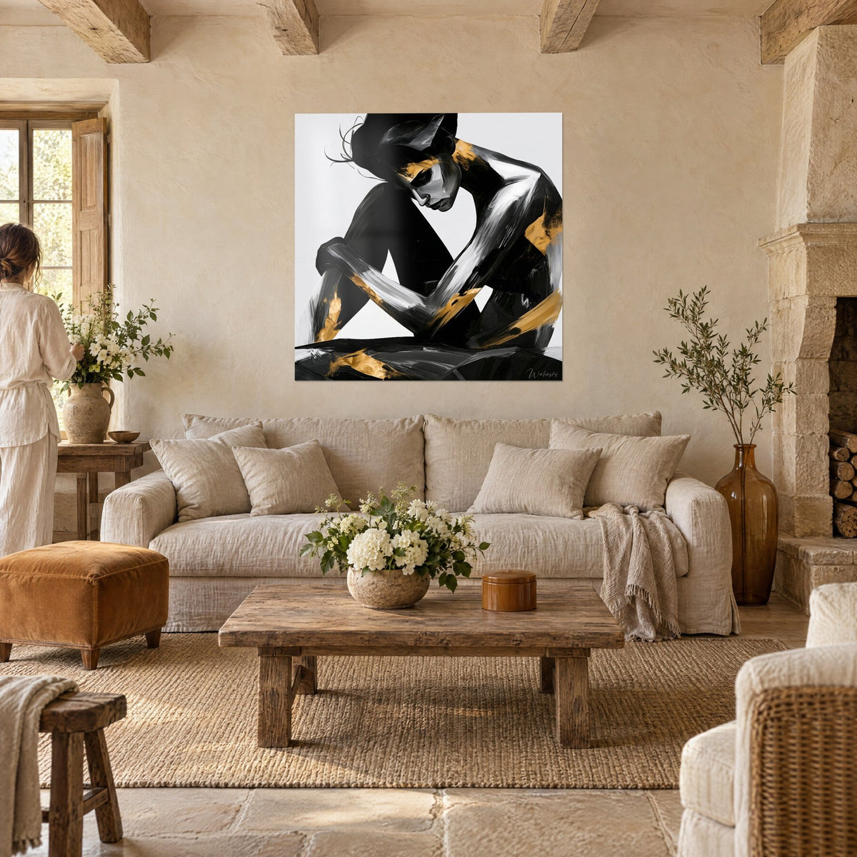 Wall art black seated silhouette with gold accents, head bowed onto knees, white background, above a sofa in a bright living room