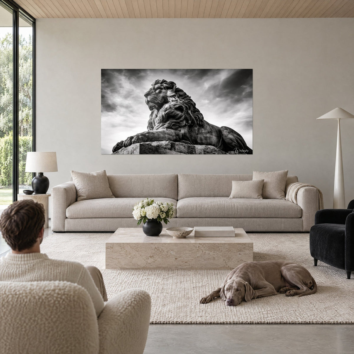 Quadro leone di pietra in bianco e nero, criniera scolpita sotto un cielo grigio di tempesta, sopra un divano in un soggiorno luminoso