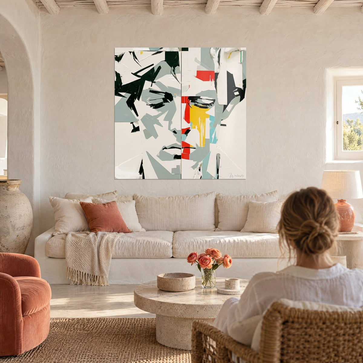 Tableau visage fragmenté en facettes grises et blanches, coulée jaune et aplat rouge, au-dessus d'un canapé dans un salon lumineux