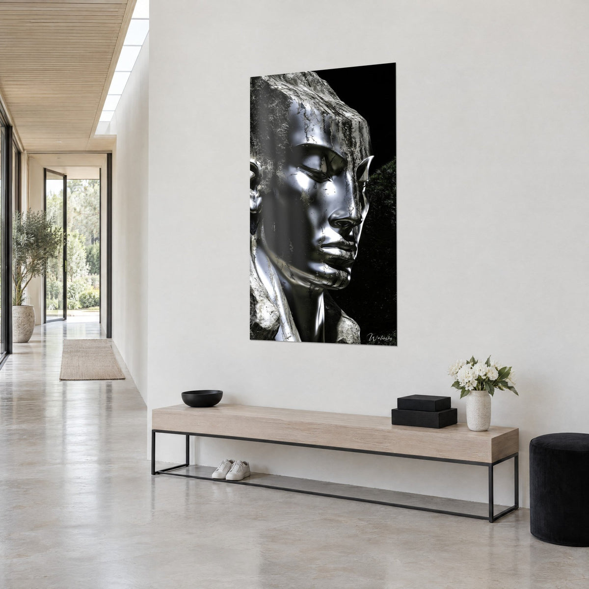 Wall art chrome-plated metal mask and cracked rock, lowered gaze, deep black background, three-quarter view in a light beige hallway