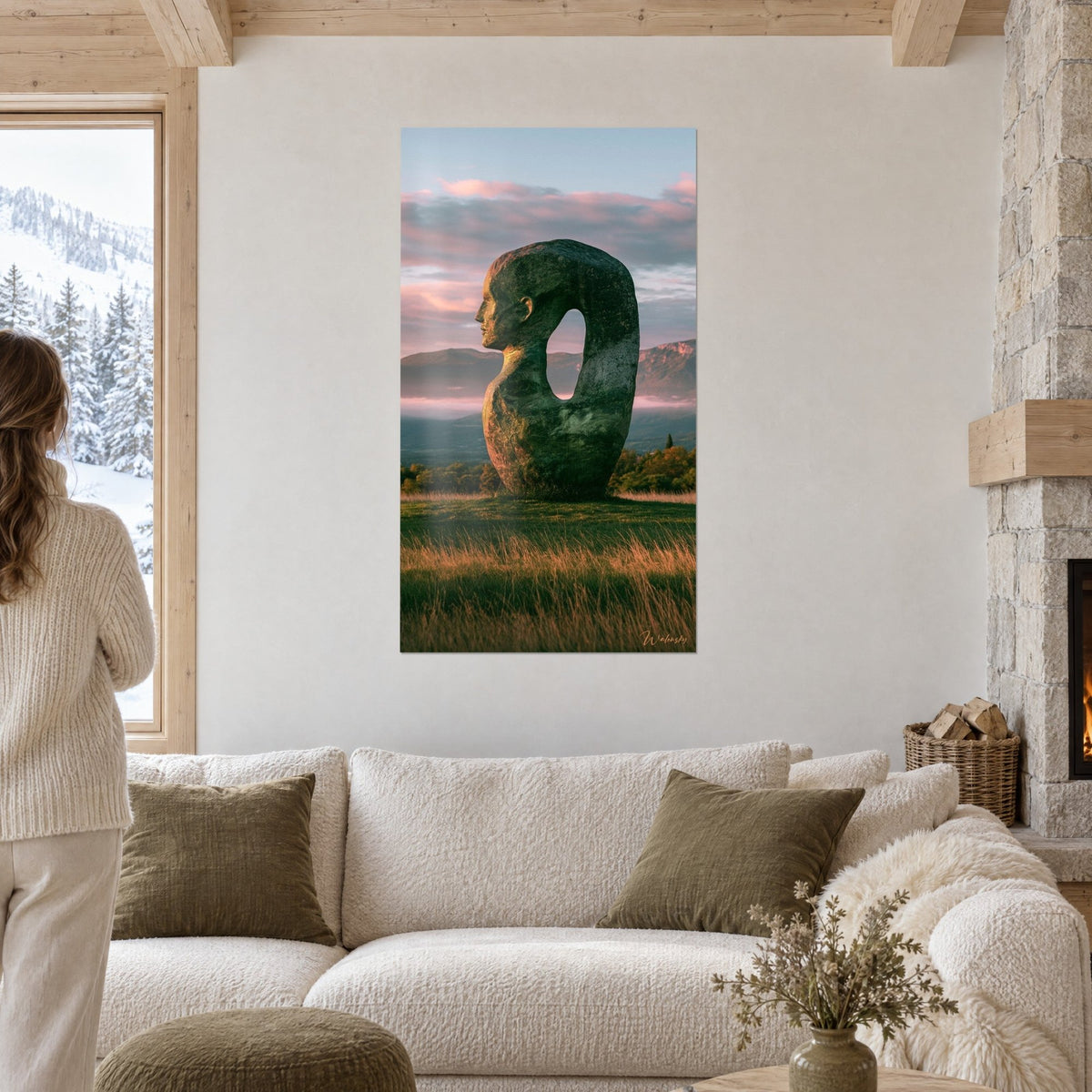 Tableau statue monumentale de pierre verte au profil humain, ciel rose et brume, au-dessus d'un canapé dans un salon lumineux