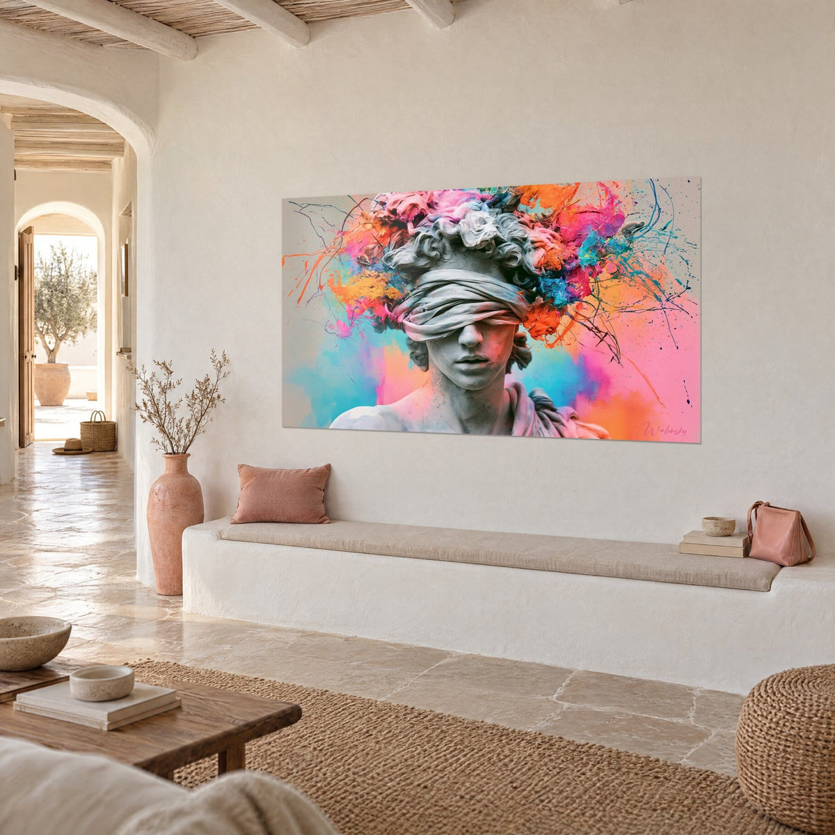 Cuadro estatua con venda gris perla en los ojos, salpicadura de pintura naranja y rosa, en la pared de una casa mediterránea de piedra clara