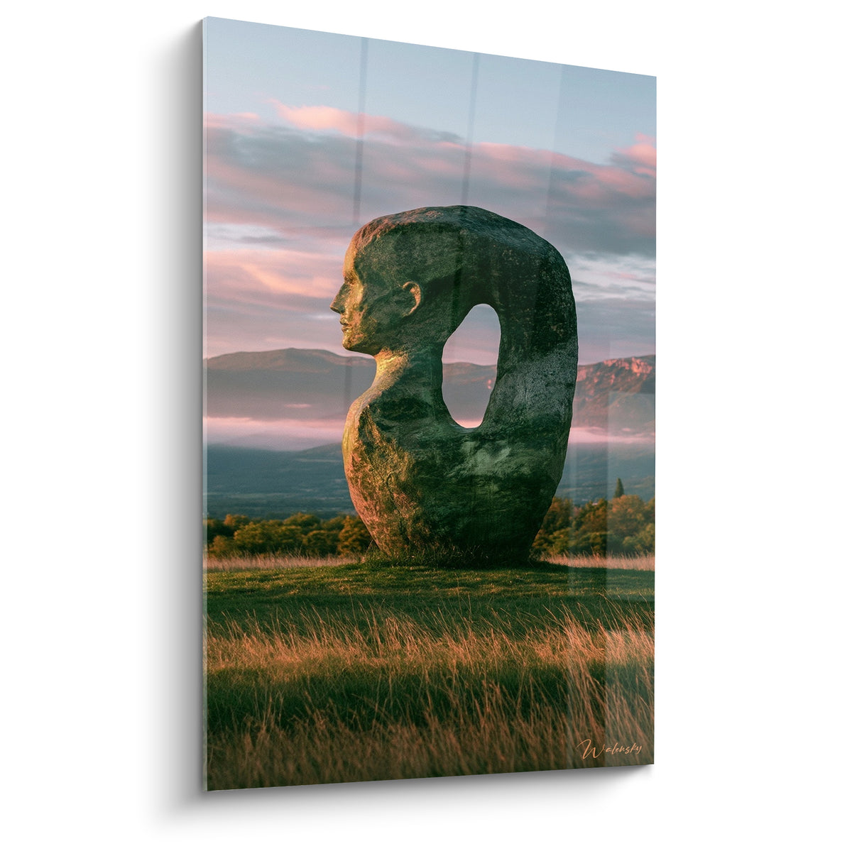 Statue au profil humain vert mousse et rose, silhouette ovale percée face aux montagnes