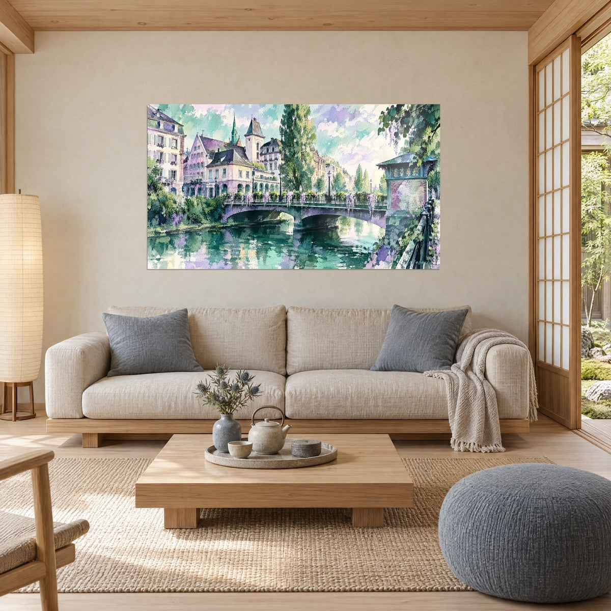 Wall art of a mauve stone bridge spanning a green canal, hanging wisteria, pink façades, above a sofa in a bright living room