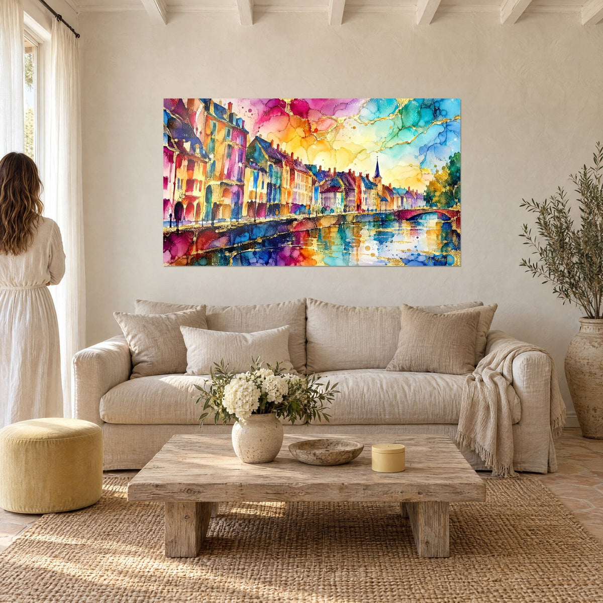 Schilderij kade met fuchsia en turquoise huizen, verre kerktoren, gouden weerspiegelingen op het water, boven een bank in een lichte woonkamer