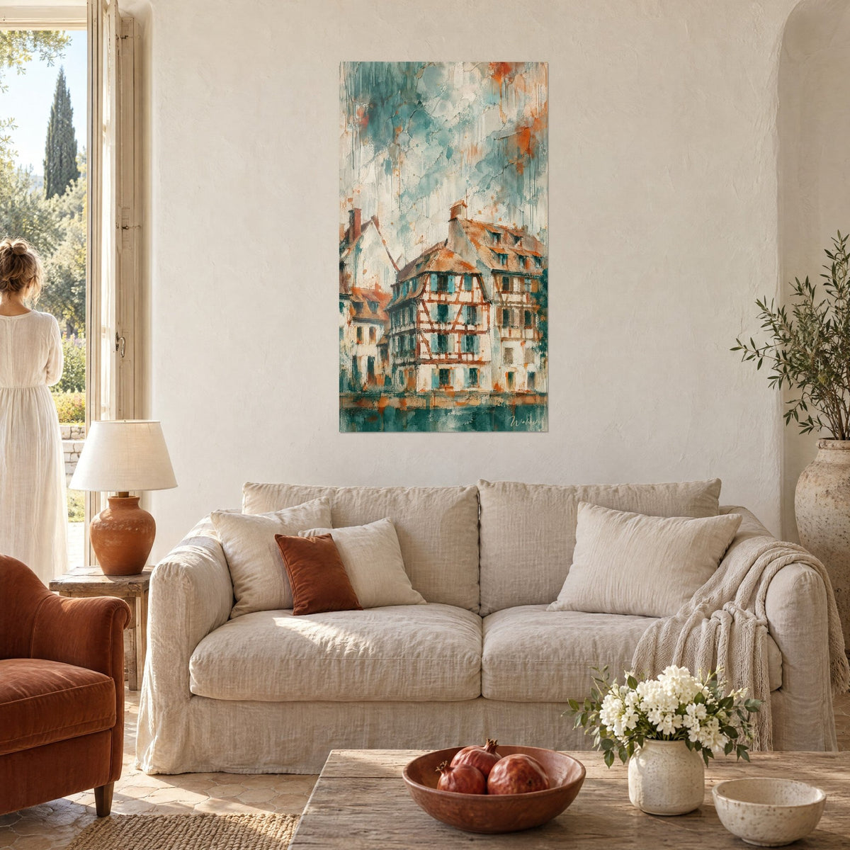 Gemälde mit einem Fachwerkhaus, rostfarbene Balken und petrolblaue Fensterläden, verwaschener Himmel, über einem Sofa in einem hellen Wohnzimmer