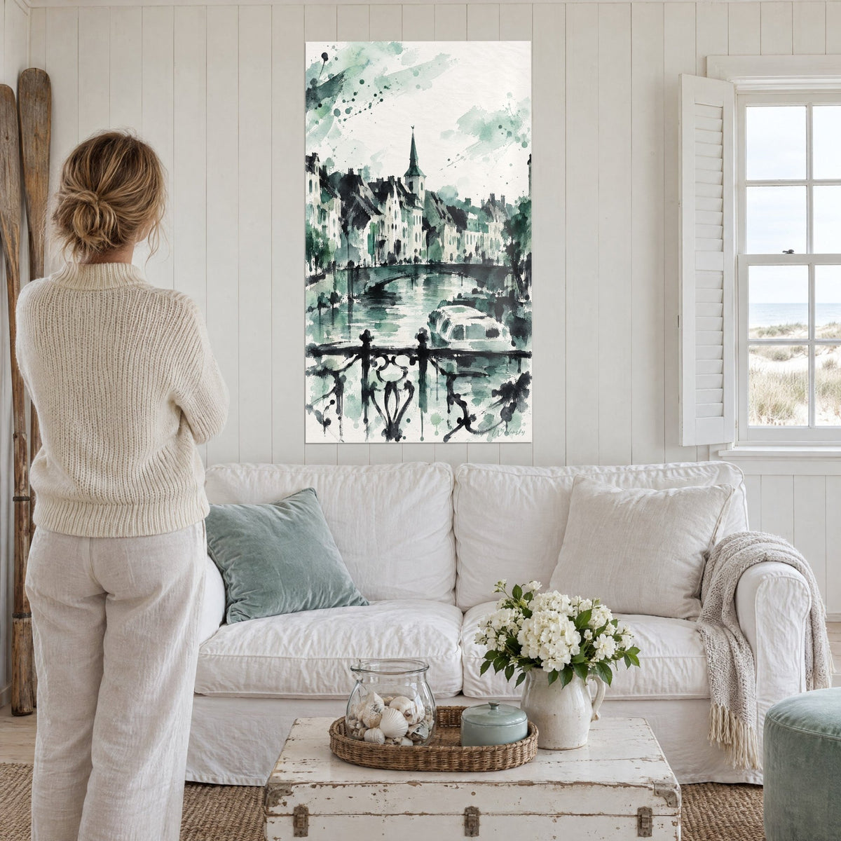 Gemälde Kanal in Aquarell mit weißen Häusern und blaugrünem Kirchturm, schmiedeeiserne schwarze Brüstung, über einem Sofa in einem hellen Wohnzimmer