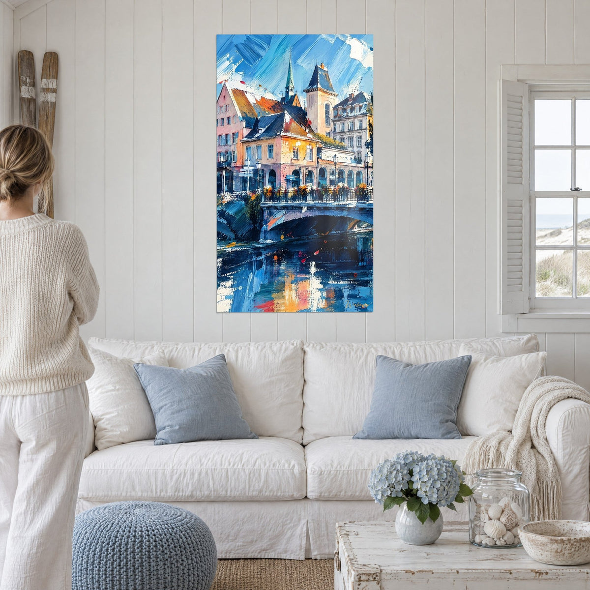 Schilderij stenen brug met blauwe bogen, oranje daken en een hemel vol messteken, boven een bank in een lichte woonkamer